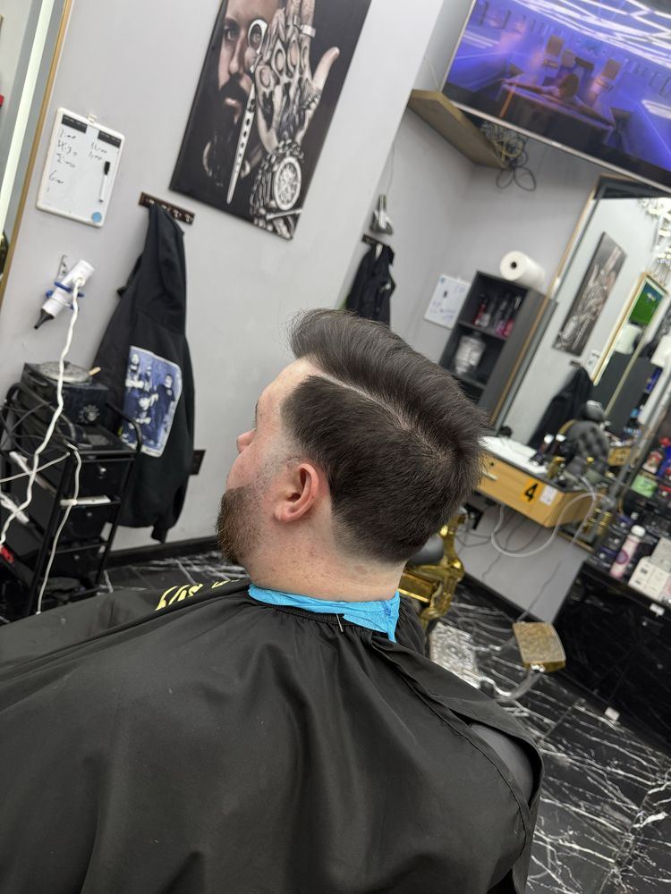 Side-part pompadour with a hard part and faded sides, in the barber chair